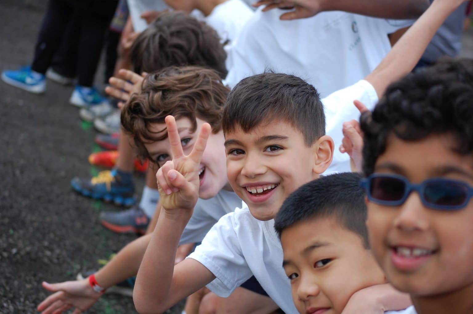 Group of smiling children, one giving the peace sign to the camera.
