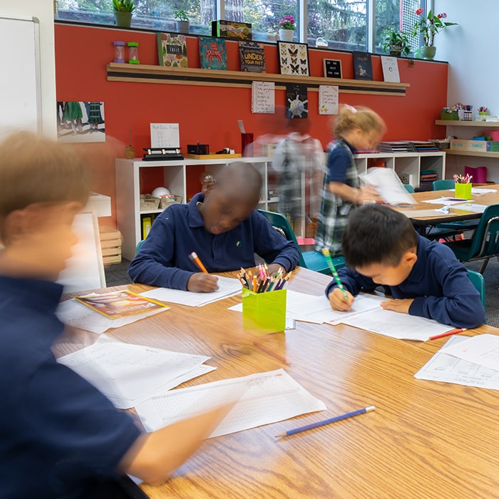 Image of a busy Elementary classroom, many children working at tables.