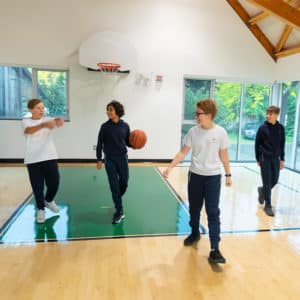 A group of Middle School children playing basketball in the gym.