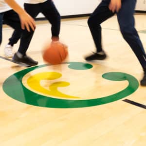 The Clanmore logo on the gym floor, amongst children playing basketball.