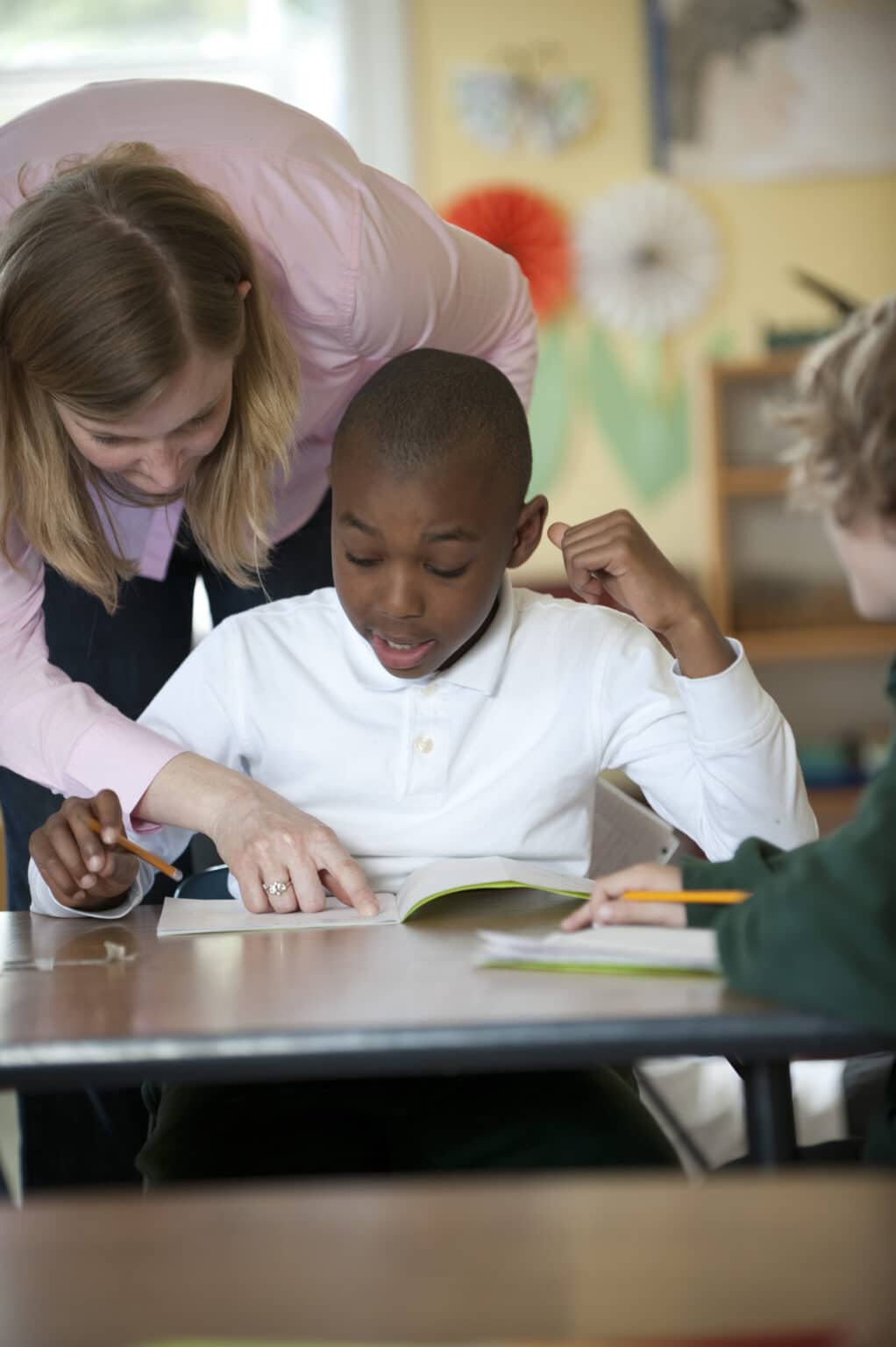 An Elementary child receives support from a teacher in his spelling work.