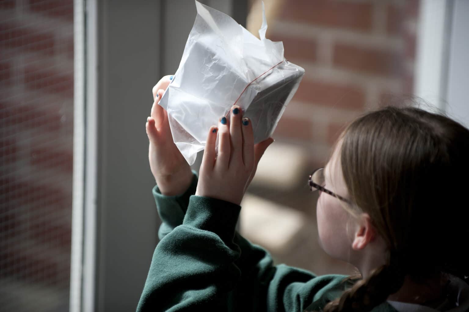 An Elementary student peers into a hand-made pinhole camera.