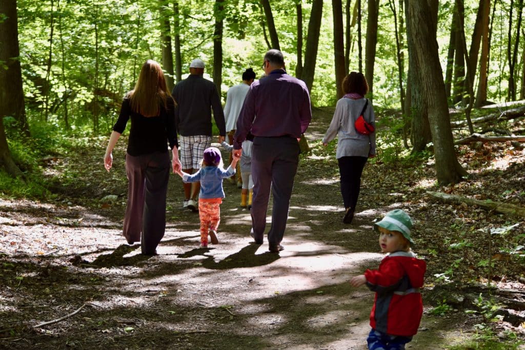 Adults and children going for a walk in the woods on a spring day.